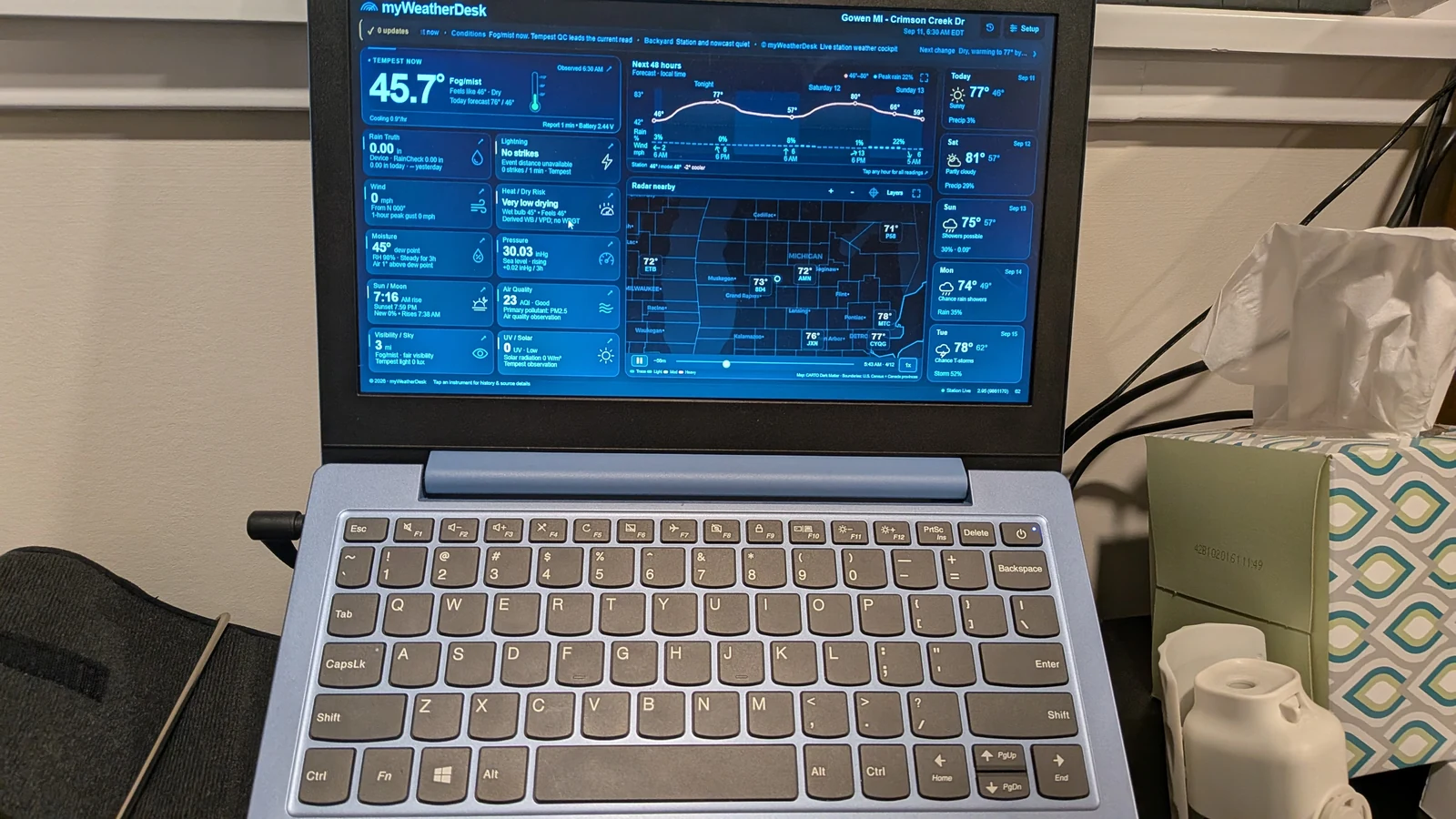 A user's laptop displaying myWeatherDesk beside a window